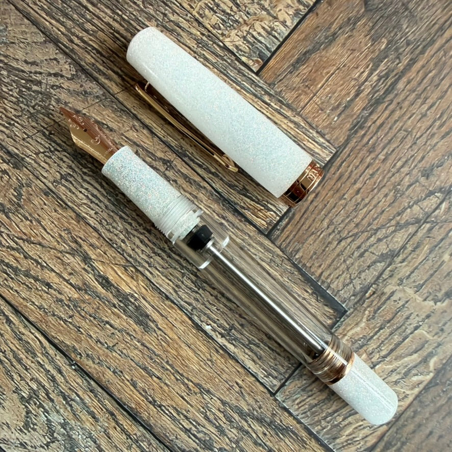 Nahvalur Original Plus Matira Quartz fountain pen uncapped, showing the rose gold nib, clear barrel and shimmering white cap