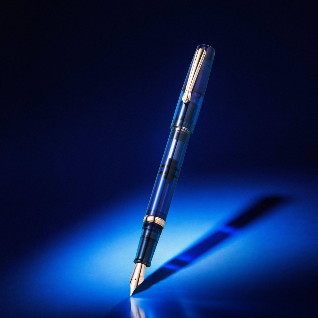Nahvalur Original Sapphire Night fountain pen in transparent sapphire blue resin, lit against a dark blue background