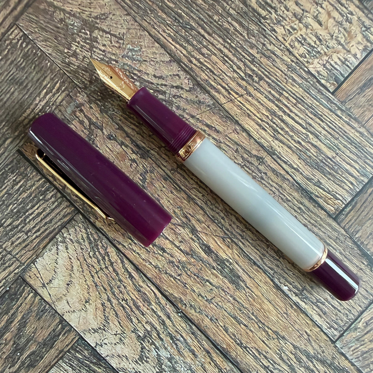 Nahvalur Original Violet Ash fountain pen uncapped, showing its gray barrel, deep violet cap and grip, and rose gold trim