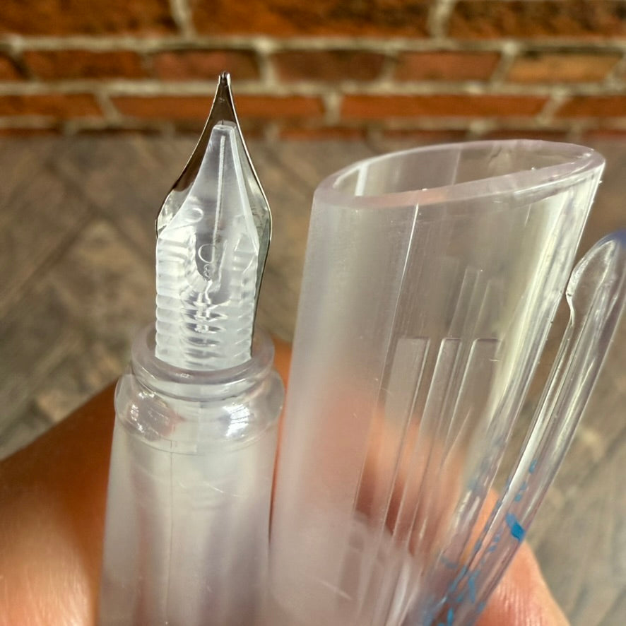 Side view of the Nahvalur Triad nib and clear feed beside its transparent cap