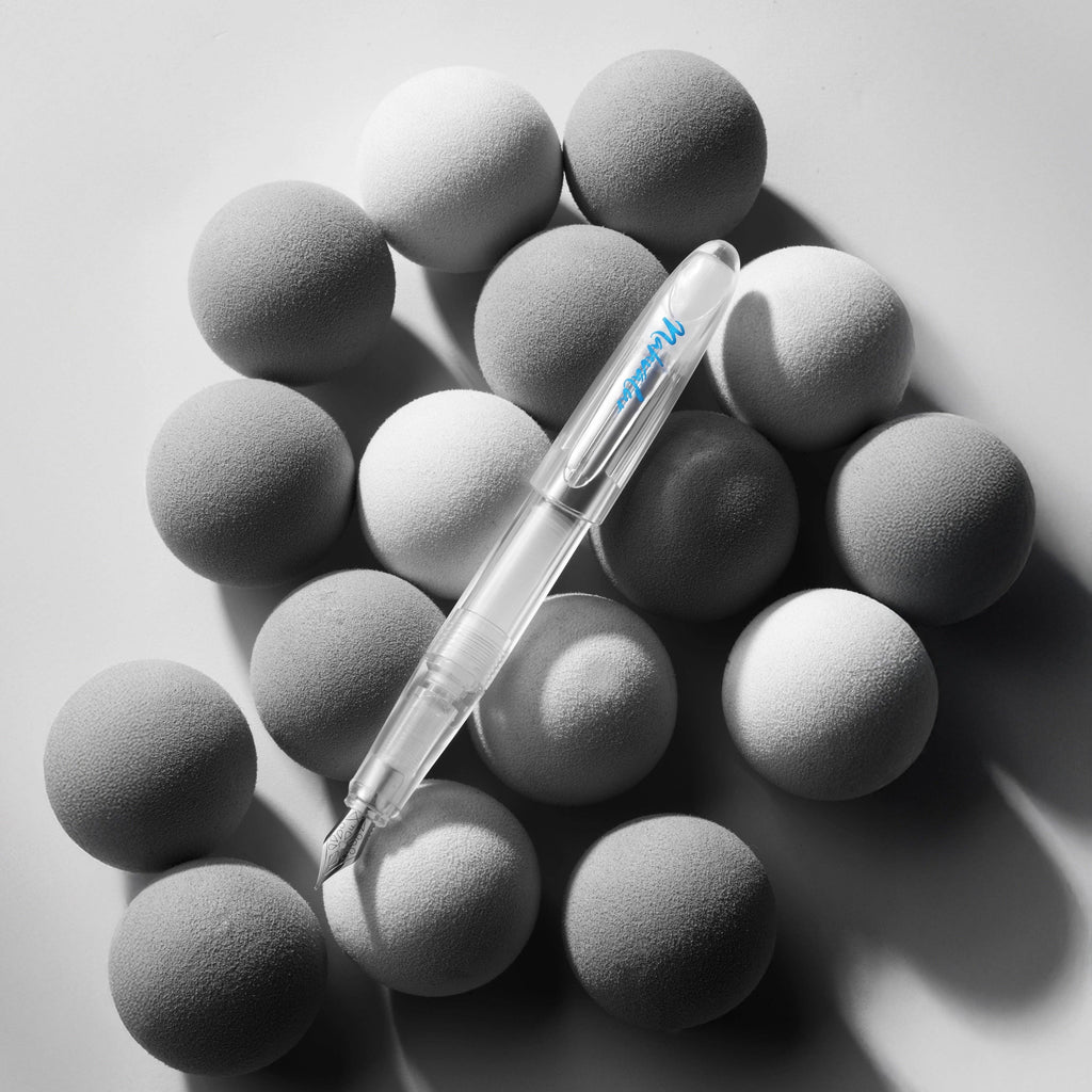 Nahvalur Triad clear demonstrator fountain pen resting on grey felt spheres