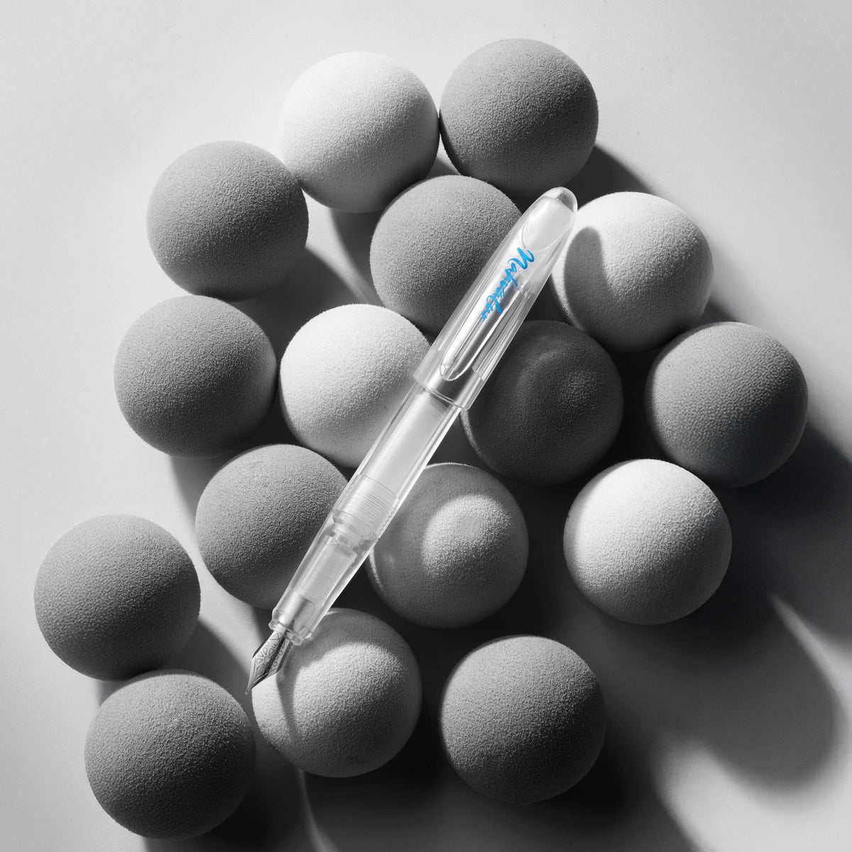 Nahvalur Triad clear demonstrator fountain pen resting on grey felt spheres