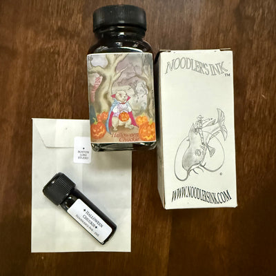 Noodler's Halloween Chuckie 5 mL Archive Bottle on a glassine envelope beside the original illustrated Noodler's bottle and box