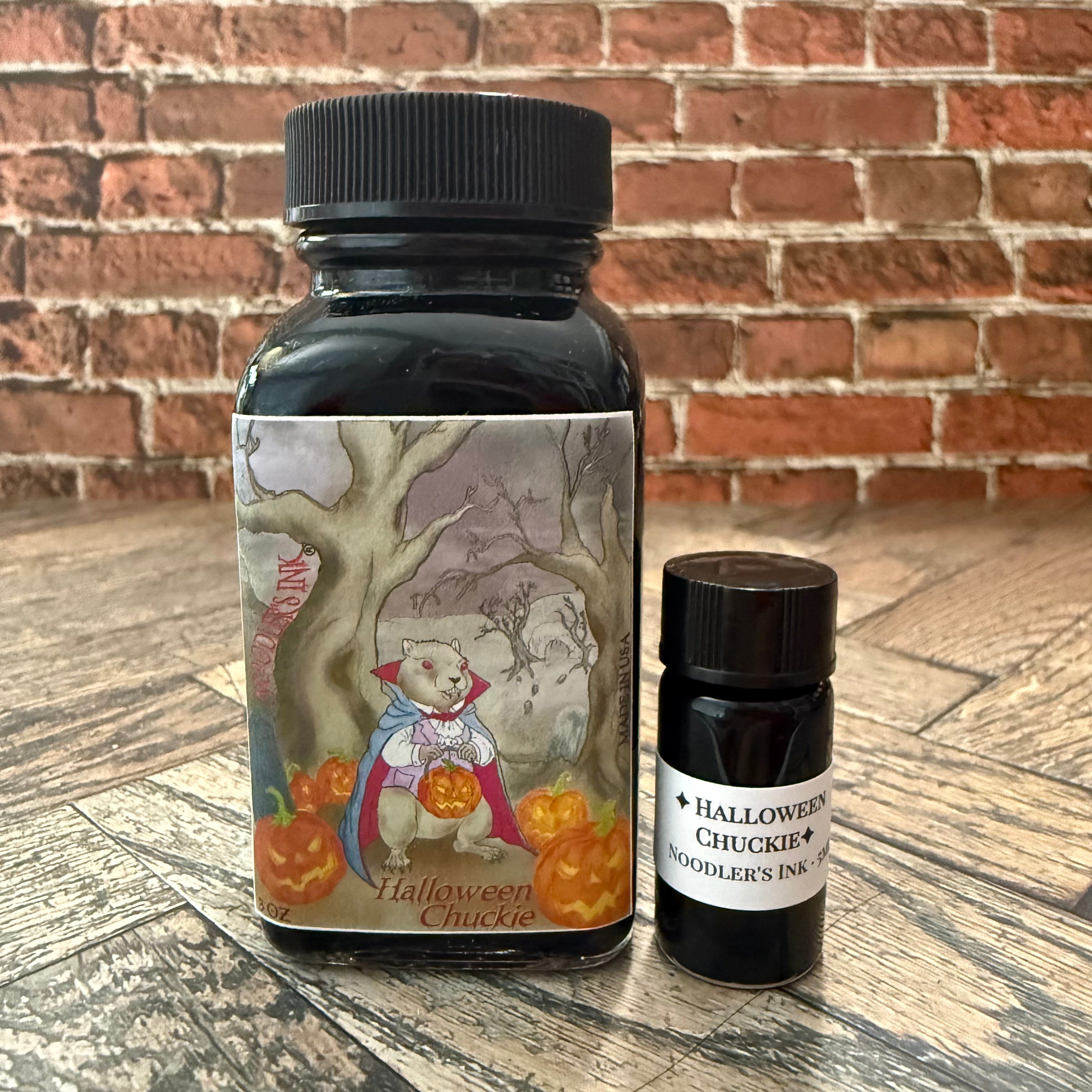 Noodler's Halloween Chuckie 5 mL glass specimen bottle beside the full 3 oz bottle with its caped woodchuck and jack-o'-lantern label (full bottle not included)