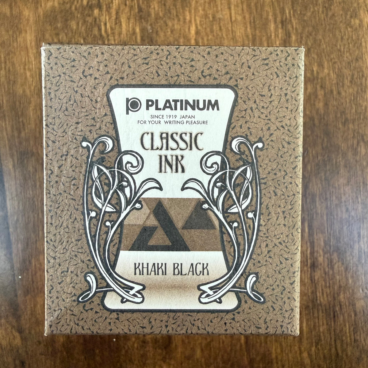 Platinum Classic Khaki Black 60 mL ink box with ornamental black-and-white artwork on brown patterned packaging, photographed on a wooden surface.