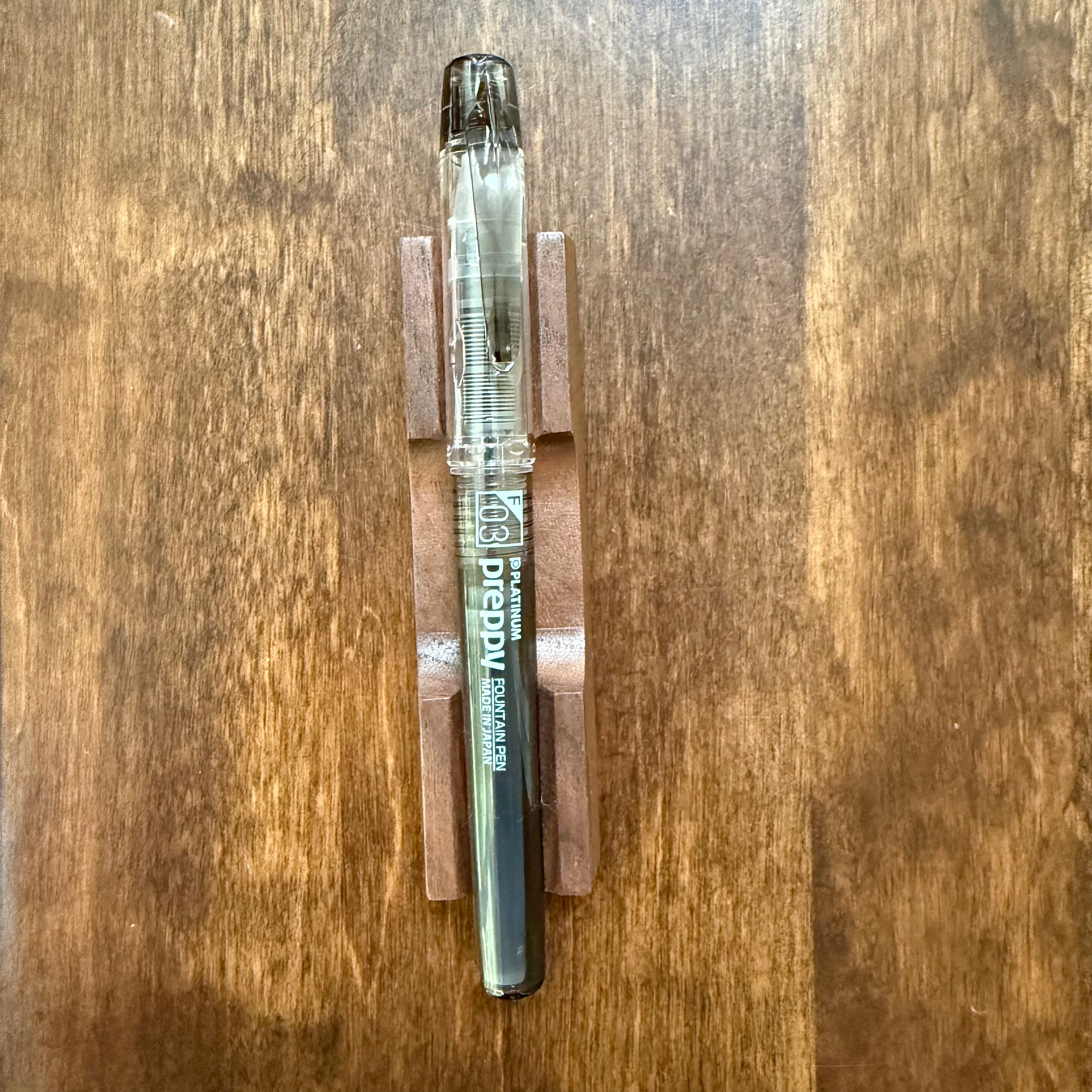 Full view of Platinum Preppy Black fountain pen with Fine 03 nib on a wooden desk