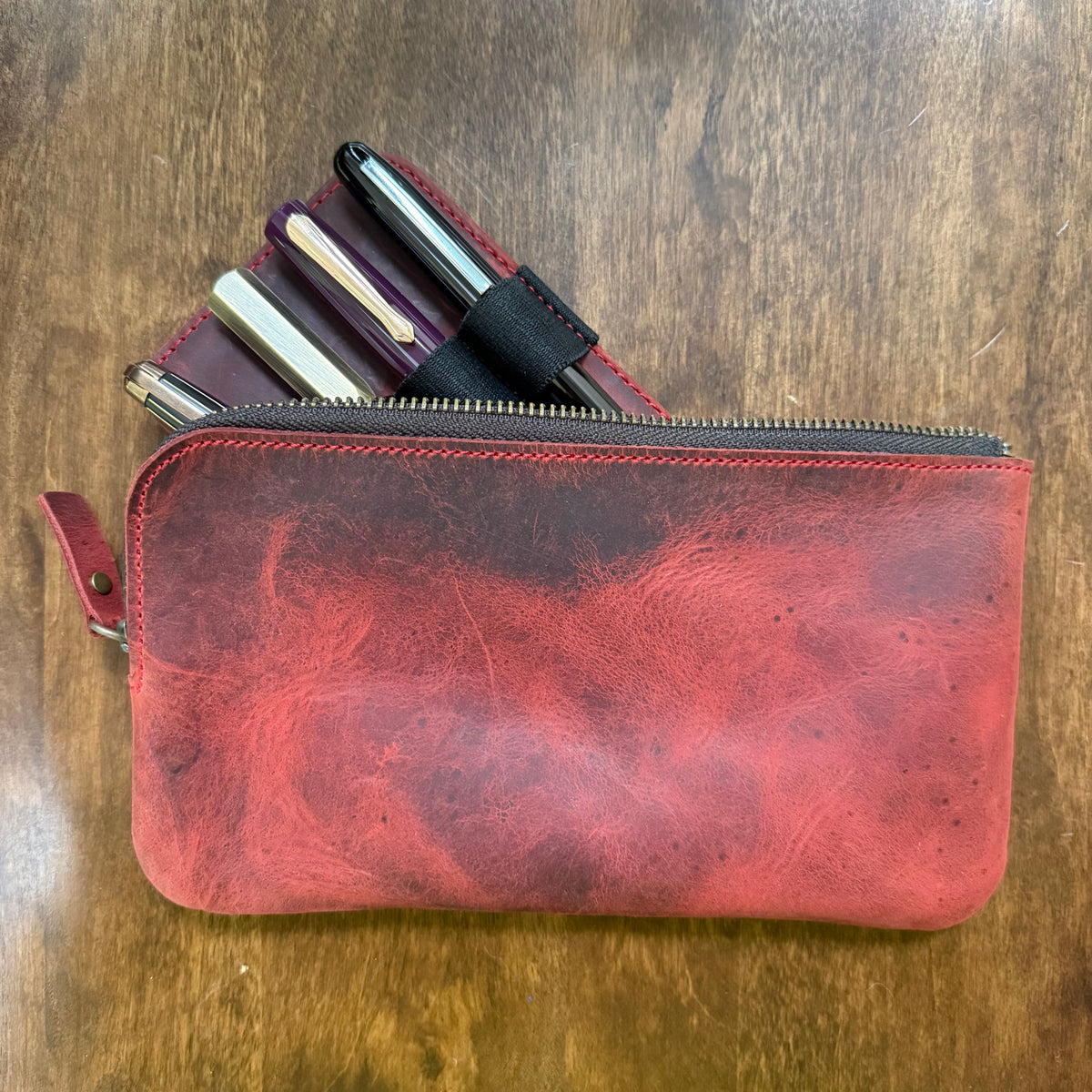Red cowhide leather zippered pen case with fountain pens and the 4-pen leather insert tucked inside
