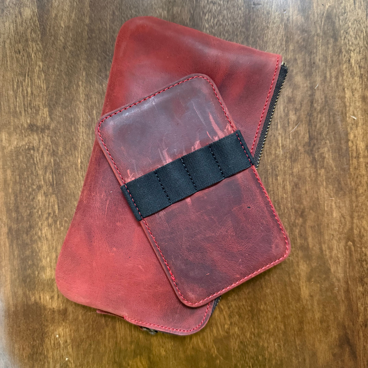 Removable leather 4-pen insert with black elastic band resting on the red cowhide leather pen case