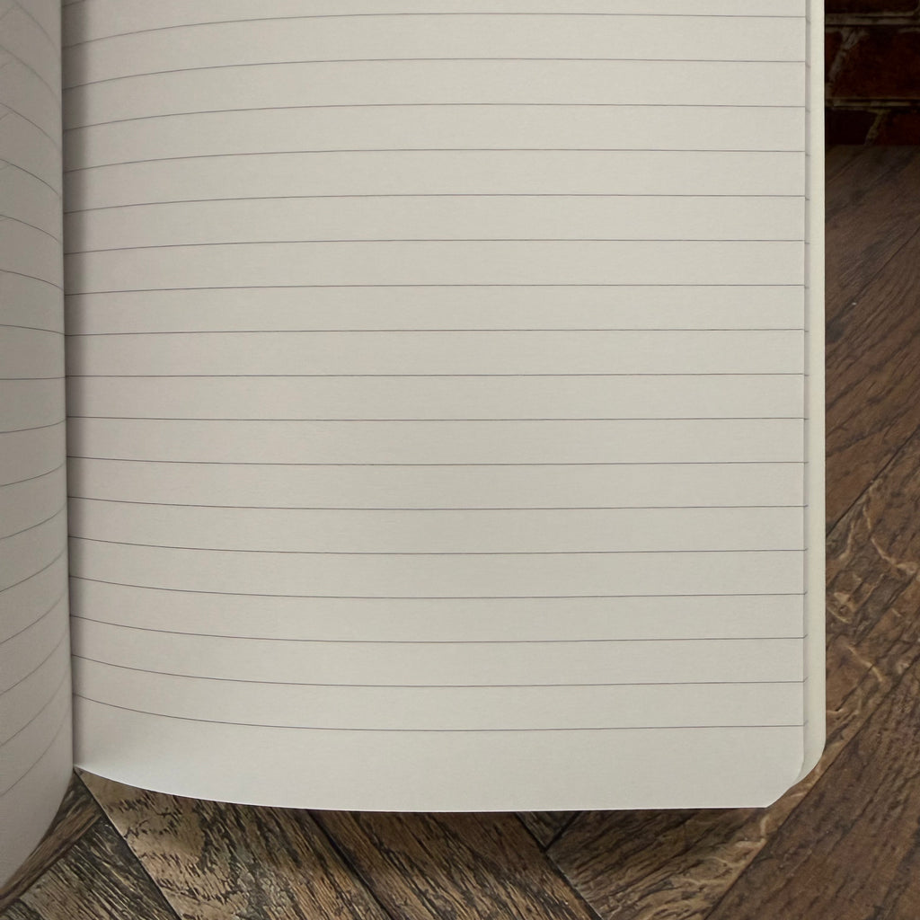Open Rhodia Ice A5 side-stapled notebook showing pale grey horizontal ruling