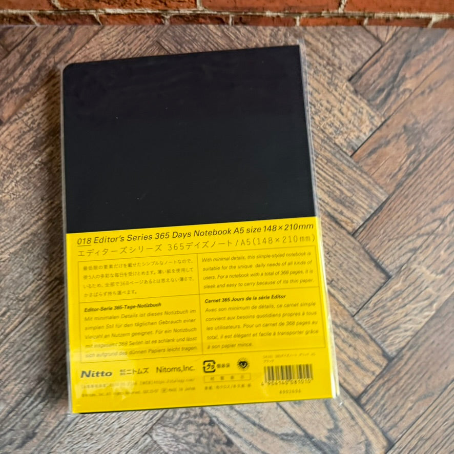 Back of the STALOGY 365Days A5 black notebook, shown at an angle with its yellow band