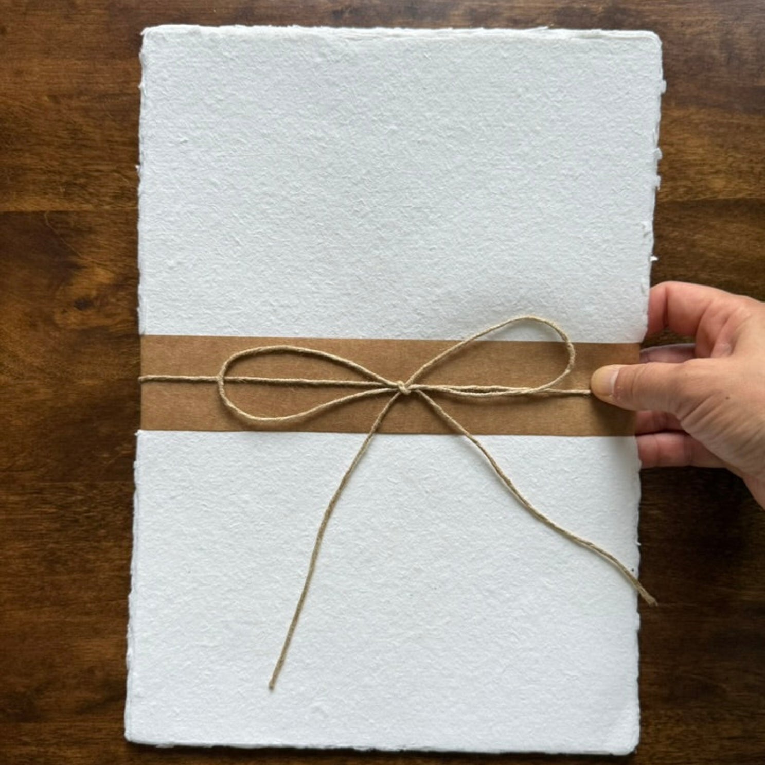 Tri-Art handmade cotton paper held in hand to show size, texture and deckled edges